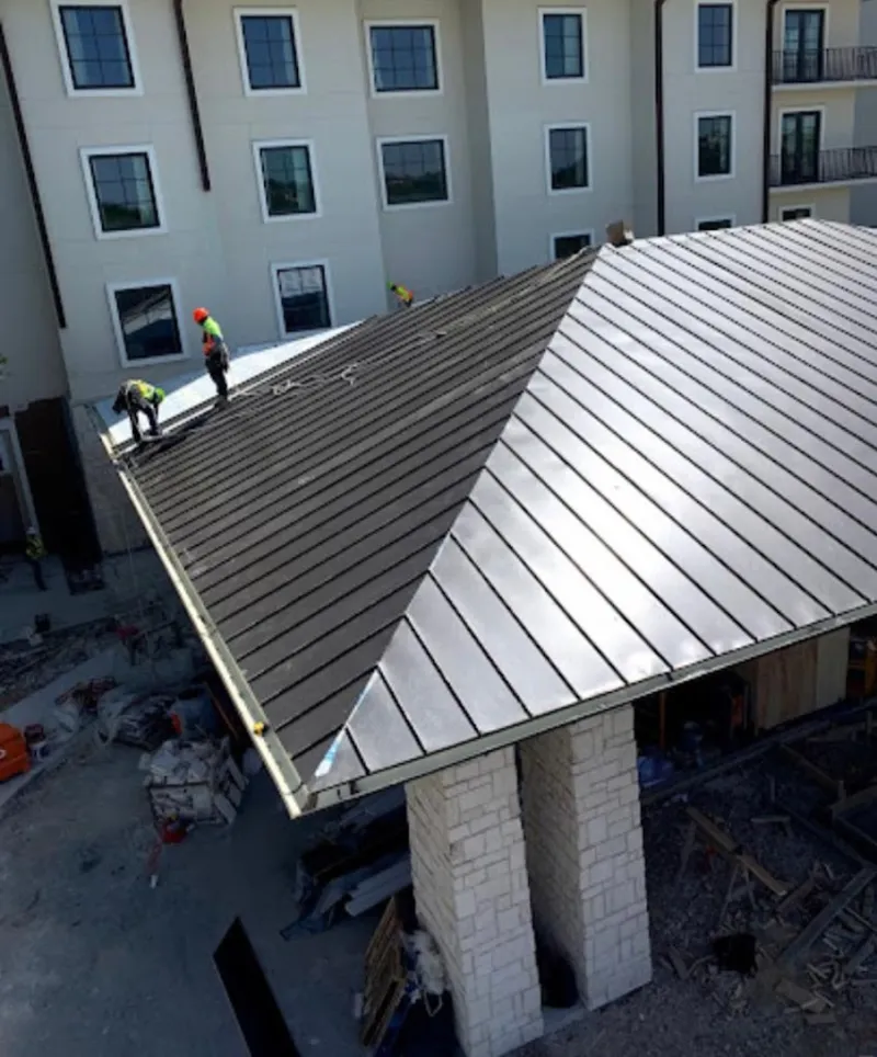 Crew installing standing seam metal roof panels on a commercial project in Dixon